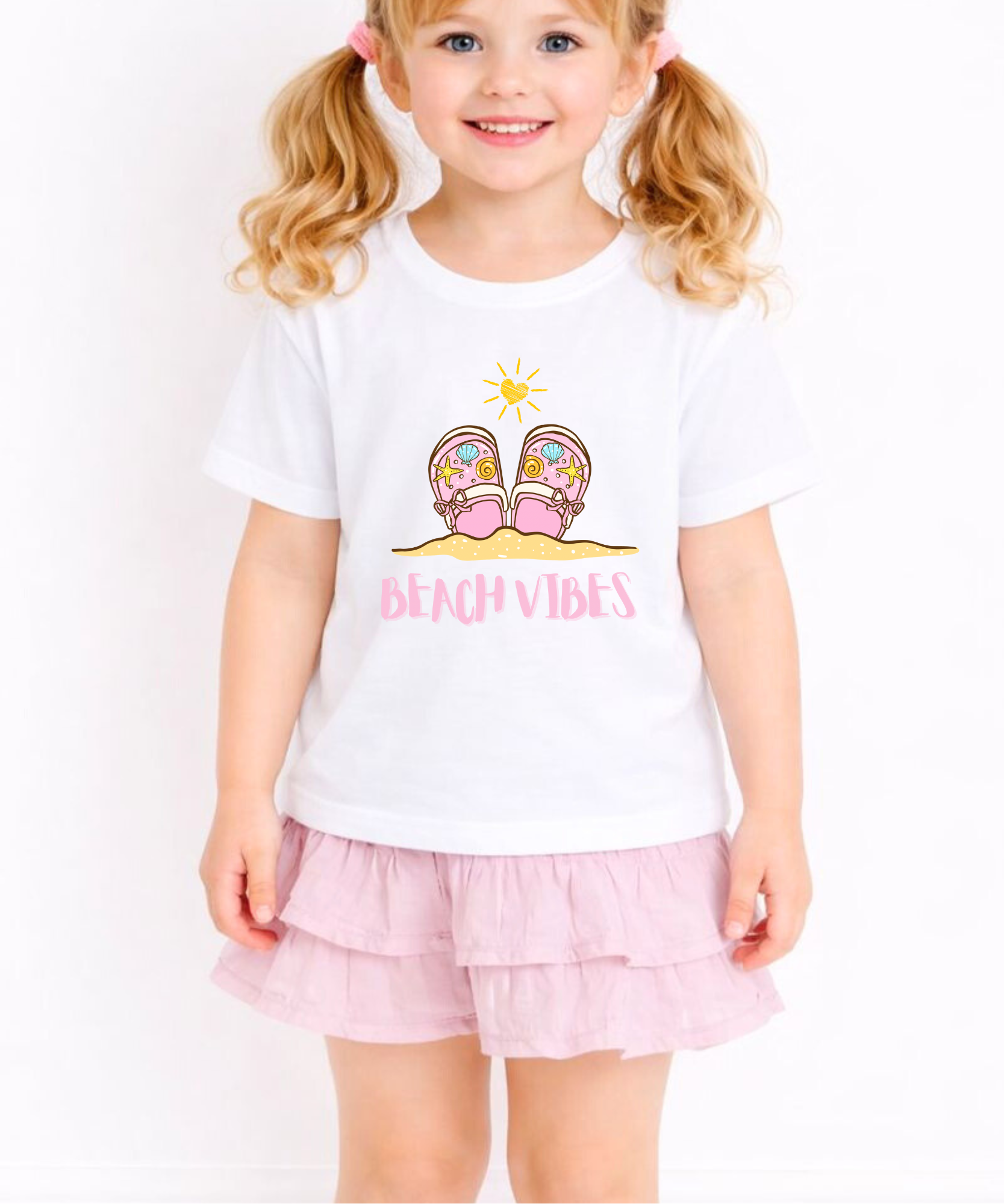 Child wearing a white t-shirt with a beach-themed design and pink shorts on a white background