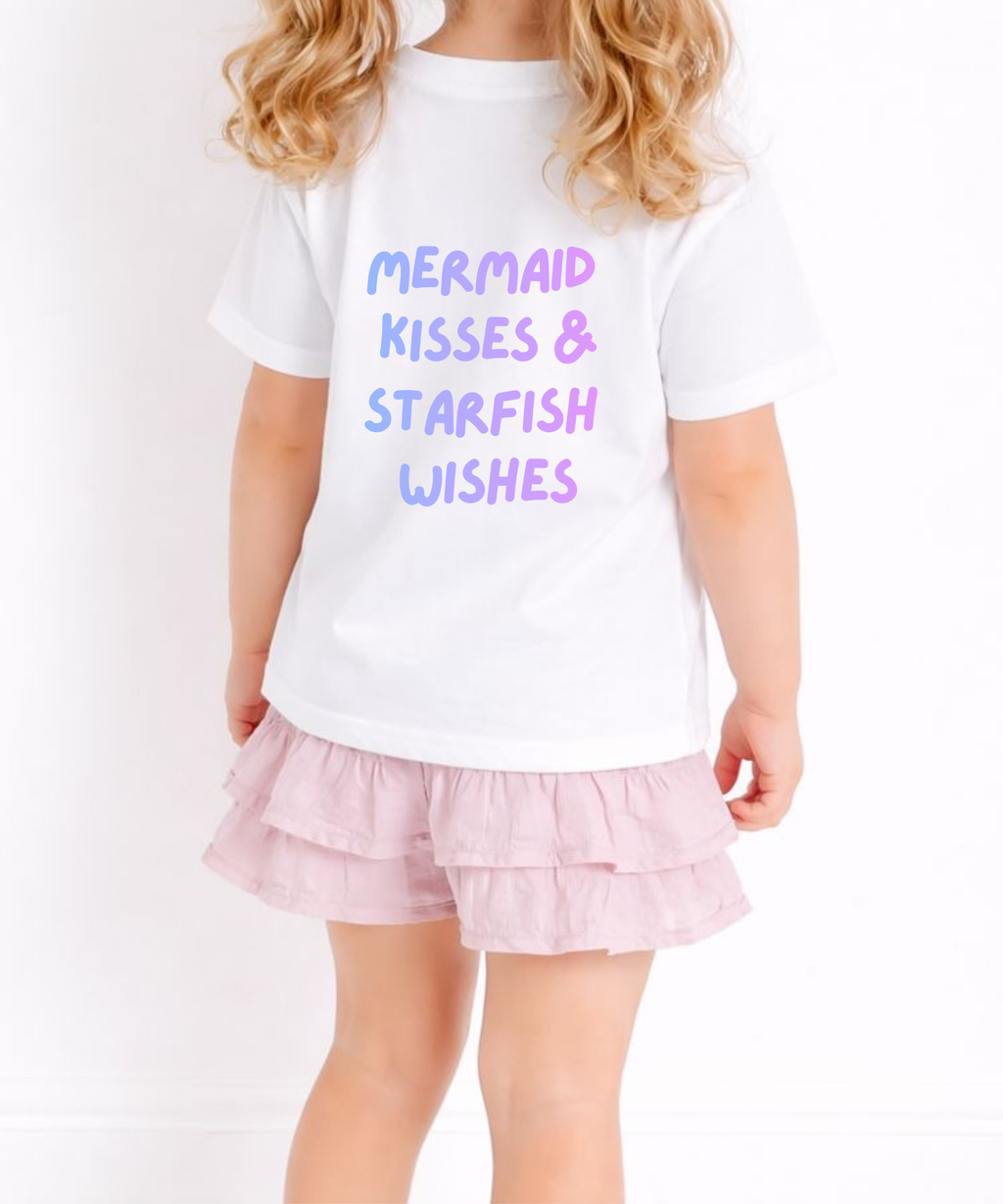 Child wearing a white t-shirt with 'Mermaid Kisses & Starfish Wishes' text and a pink skirt on a white background