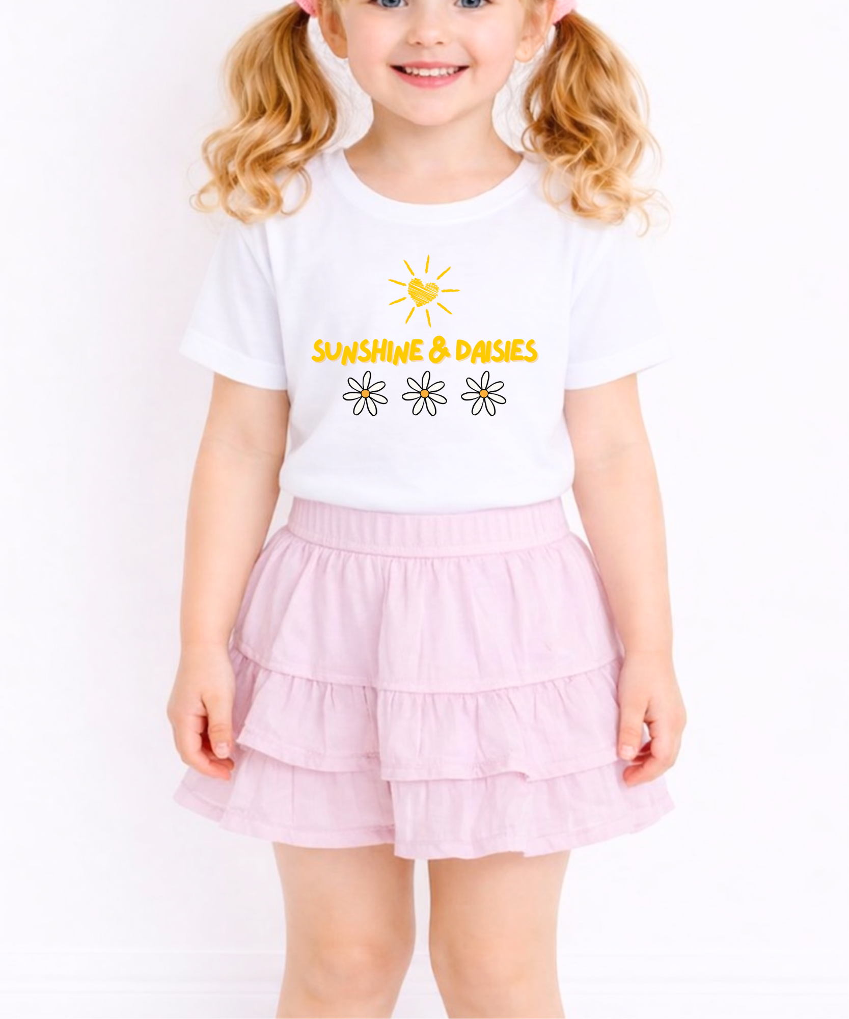 Child wearing a white t-shirt with 'Sunshine & Daisies' text and a pink skirt on a white background