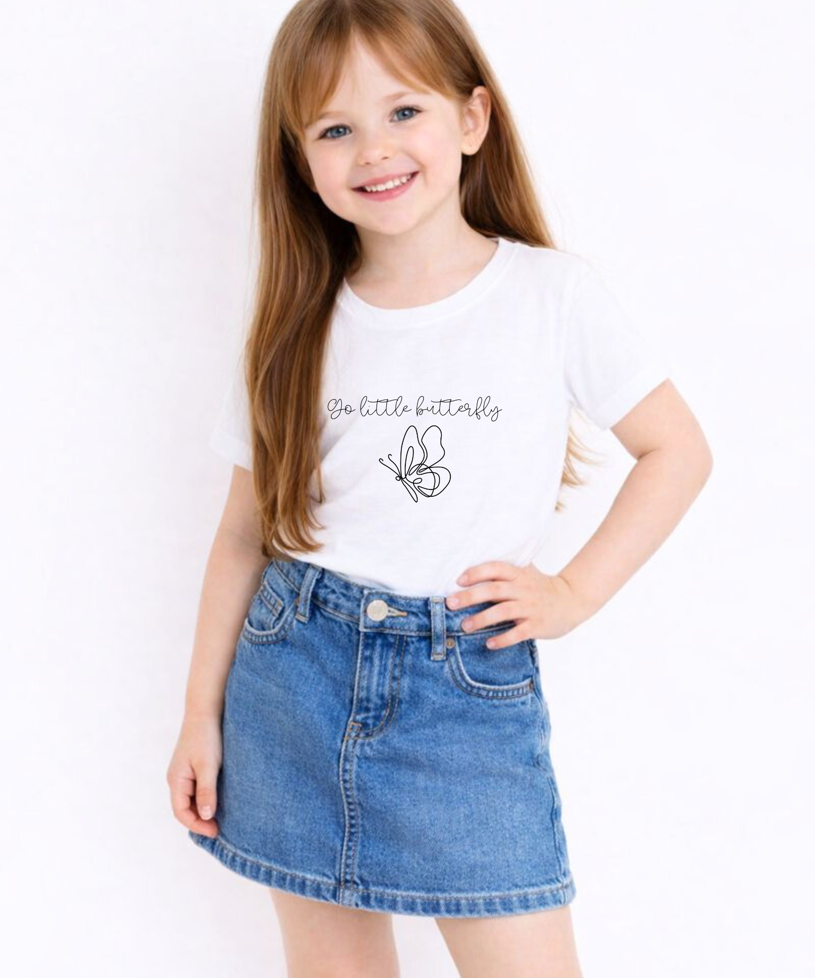 Young girl wearing a white t-shirt with text and a butterfly graphic, standing against a plain background.