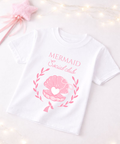 White t-shirt with pink mermaid-themed design on a white background